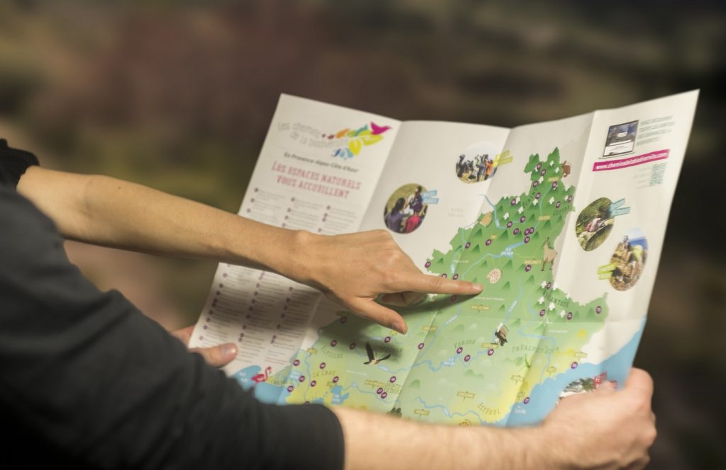 des vacanciers pointant une carte présentant les espaces naturels de la région Provence-Alpes-Côte d’Azur