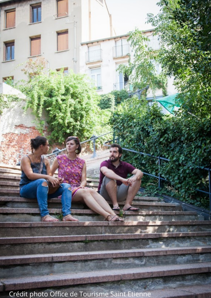 Deux touristes et un Greeter sont assis sur des marches à Saint-Etienne