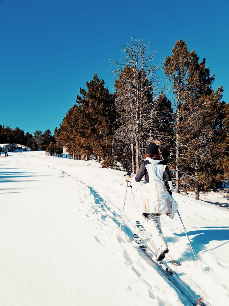 ski de randonnée à la station Puigmal 2900 - skieur en tenue blanche skiant, des arbres, une forêt en arrière fond